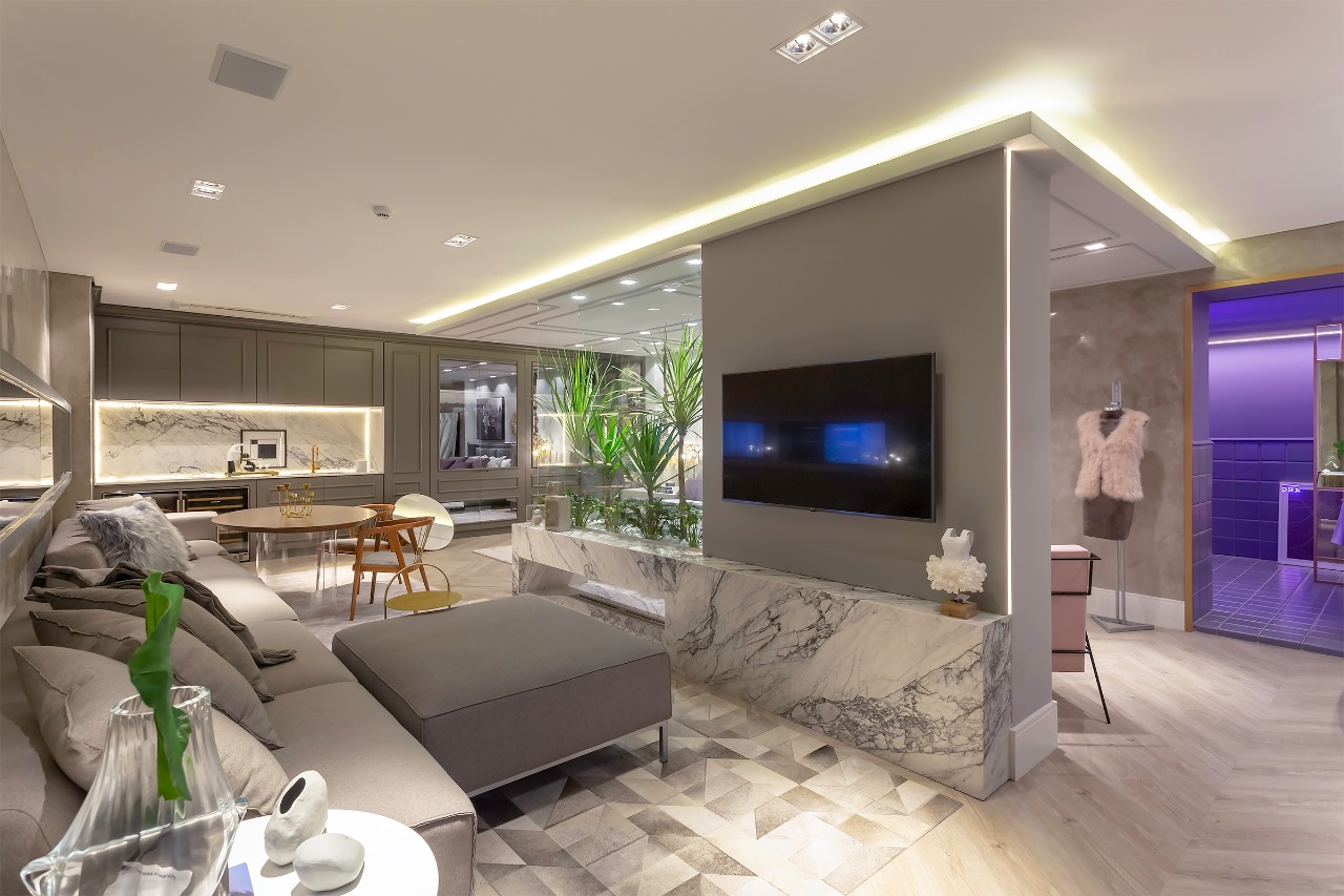 Ambiente de estar com painel de TV, bancada em mármore e jardim interno