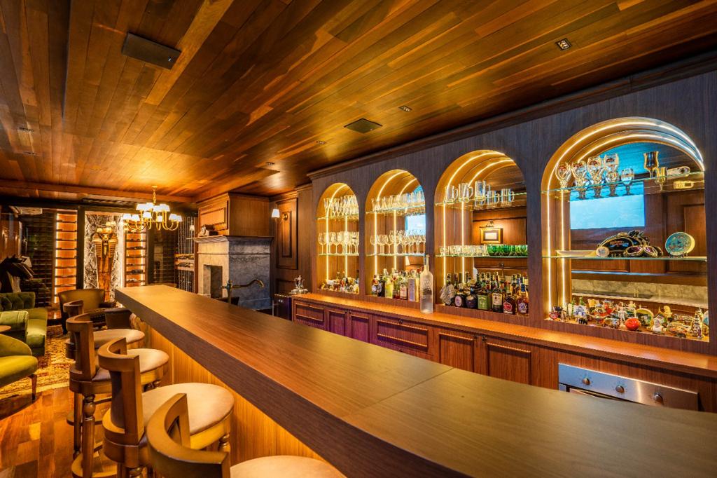 Bar privativo com arcos iluminados e forro ripado em madeira